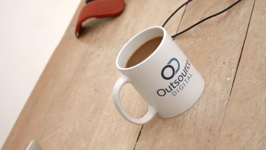 An outsource digital branded mug sits on the desk at Outsource Digital